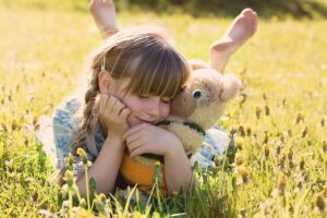 girl hugging a teddy bear in a sunflower field